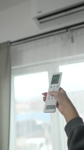 Woman hold a remote control with air conditioner.Turn on the air conditioner to cool down.