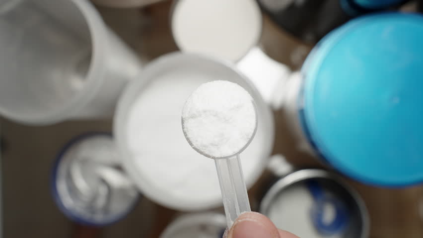 Athlete pouring Creatine powder back into the container, adjusting the amount for the correct supplementation dose. Slow motion.