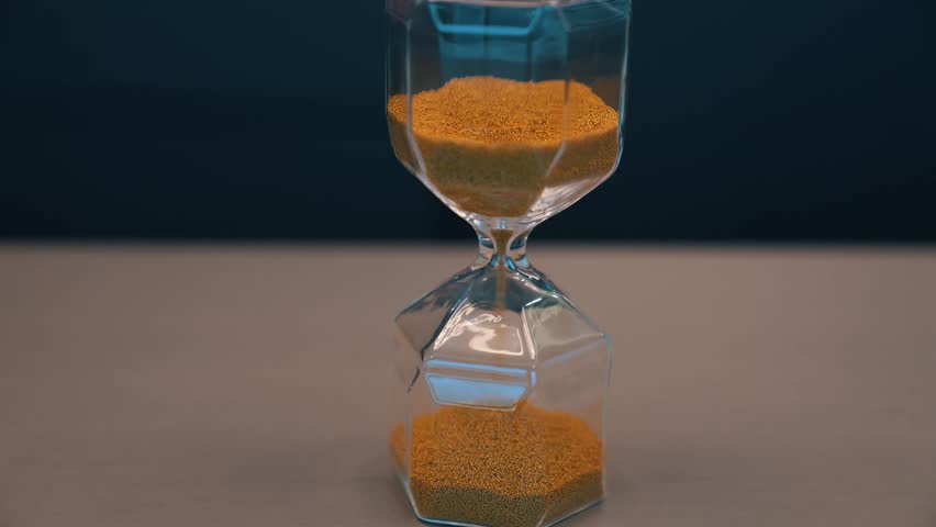 Sand clock with yellow sand flowing through glass chambers, symbolizing the passage of time, aging, fleeting moments, and philosophical concepts like mortality, life cycles, and the essence of time