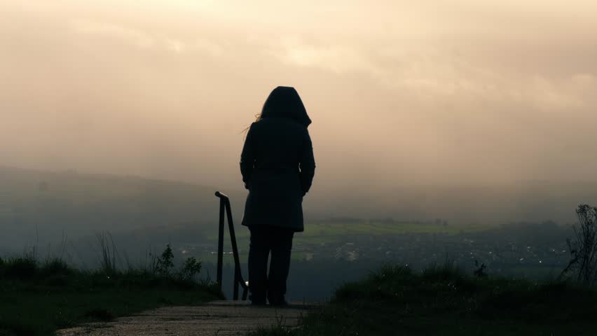 Lonely woman walking in foggy mist rural scene zoom wide shot selective focus