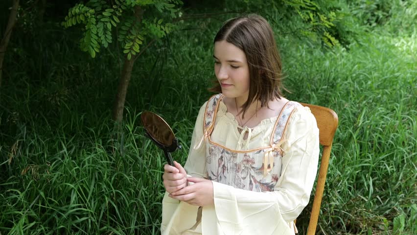 Young Woman in Renaissance Dress Gazes into Hand Mirror