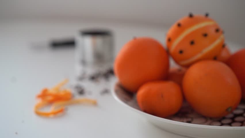 Pomander orange with cloves placed on a plate with tools in blurry background
