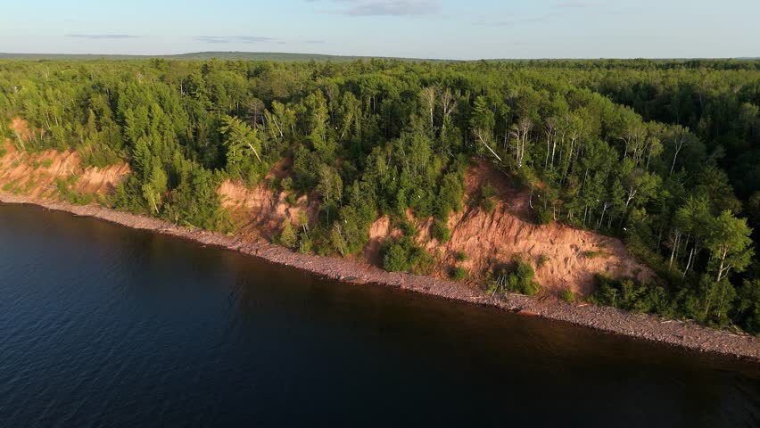 Drone view in 4K of Lake Superior red cliffs with seagulls flying along the trees above the lake