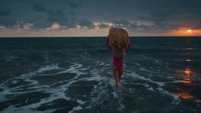 Young woman surfer walks along sand ocean beach, holds surfboard above head after sup training. Attractive girl walking or run to surfing with board. Evening dusk on bali, indonesia. Pink swuimsuit - Powered by Shutterstock - Get 15% off with code: PIKWIZARD15