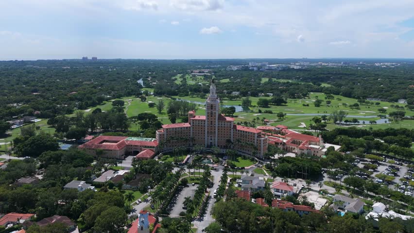 Drone view of Biltmore Hotel located in Coral Gables, Miami. Historic building with central tower and sprawling wings, surrounded by lush greenery and golf courses