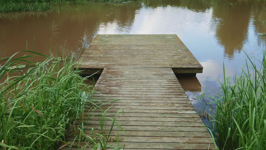 Traditional Finnish Lake Dock in Summer. Weathered Wooden Pier Amidst Natural Lake Vegetation