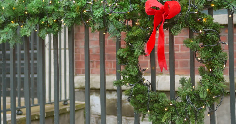 Christmas wreath with a red bow draped on fence. Closeup shot