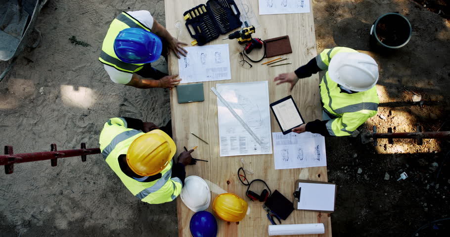 Above, people and talking on construction site with paper, urban development or project management with tech. Engineer team, blueprint or planning at equipment for building renovation in architecture