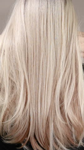 Vertical slow motion video of unrecognizable model with long blond straight hair