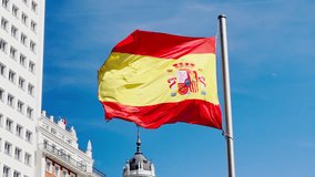 Spain's national banner flows gracefully, set against a clear sky and adjacent architecture, Madrid, Spain - Powered by Shutterstock - Get 15% off with code: PIKWIZARD15