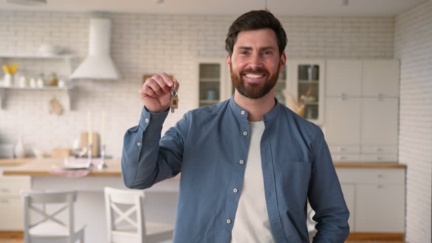 Satisfied smiling Caucasian middle-aged man homeowner guy holding show key at home happy house owner tenant male enjoy relocation rent credit glad dad buy new apartment moving household insurance loan