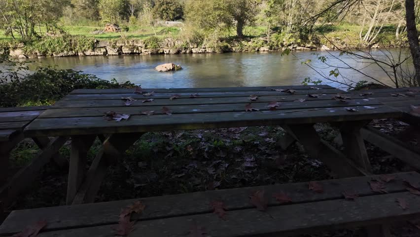 Rustic picnic table by a calm river in a forested valley