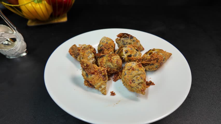 A spotted babylon snail is spinning on a white plate