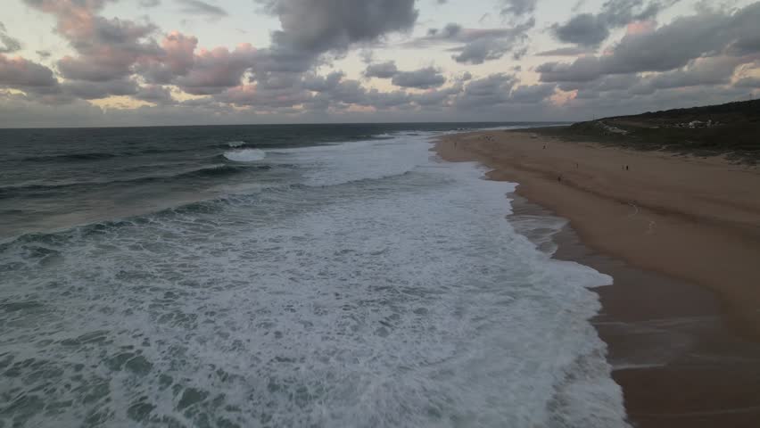 drone survolant les vagues et la plage de Nazare en automne pedant le sunset