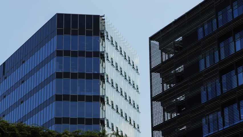 Modern glass office scyscraper buildings beautifully reflecting the clear blue sky in an urban environment