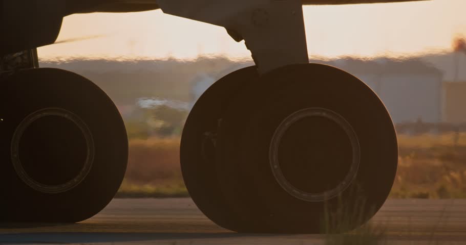 A close-up of the wheels of an airplane going to the runway at sunset. High quality 4k footage