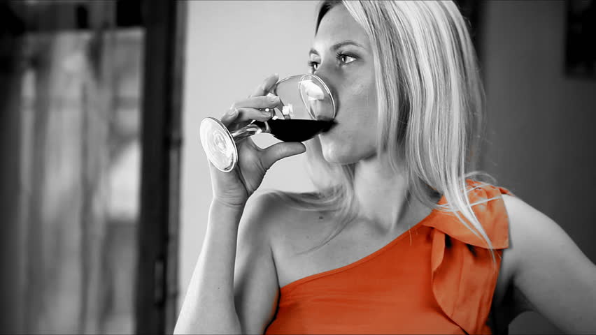 Beautiful blond woman drinks red wine in the bar