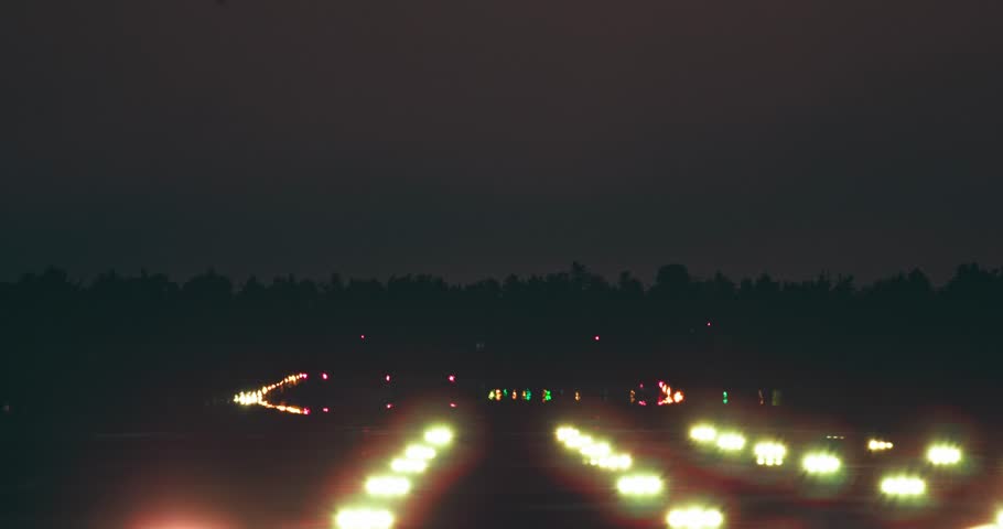 A passenger plane lands on the illuminated runway of the airport at night. Slow motion video of an airliner arriving at the airport. High quality 4k footage