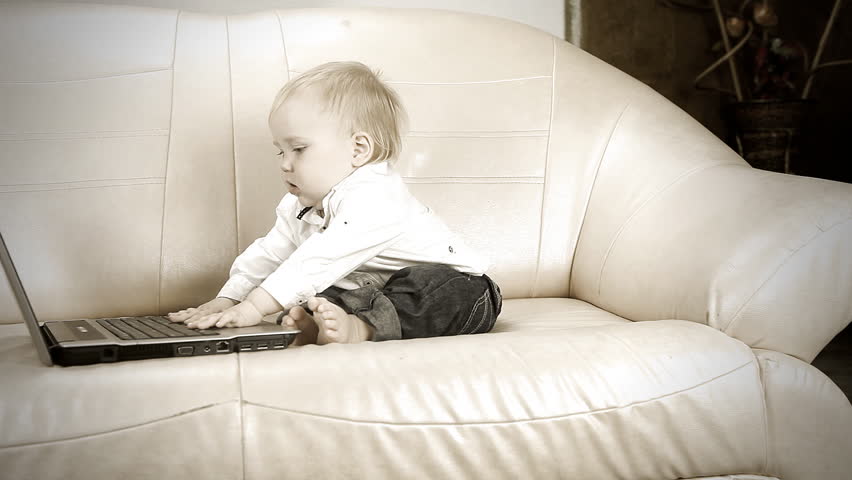 Child sitting on sofa and using laptop