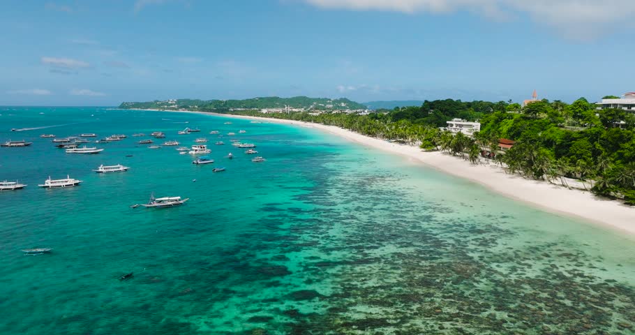Tropical white sandy beach and transparent turquoise sea water with boats. Boracay, Philippines.