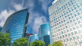 Timelapse of modern office buildings. Glass skyscrapers with reflections and highlights against a bright blue sky, framed by green trees in a park. Sunlight and passing clouds in Brussels, Belgium - Powered by Shutterstock - Get 15% off with code: PIKWIZARD15
