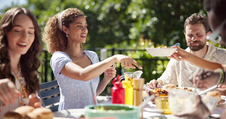 Food, party and barbecue with friends in garden for celebration, summer vacation or lunch. Share, bonding and eating with group of people on patio of home for social event, reunion and bbq together