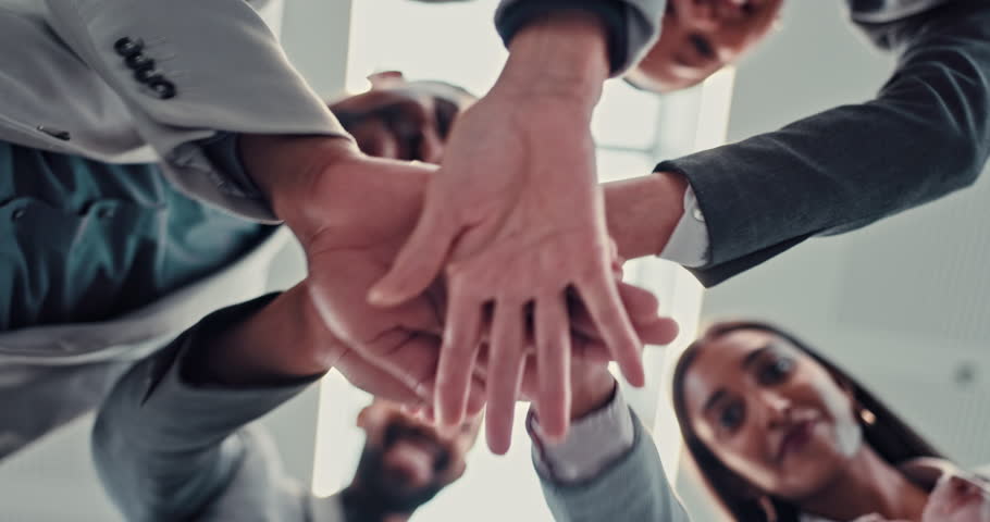 Business people, hands together or meeting below with motivation for teamwork, mission or collaboration at office. Low angle, group or employees piling for unity, solidarity or agreement at workplace
