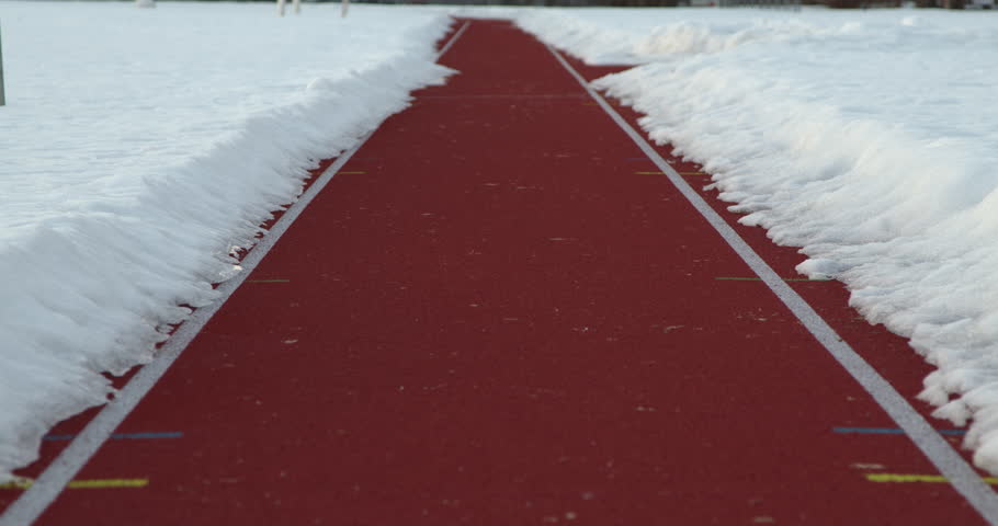 Snow-Lined Running Track in Winter, Athletic Stadium Lane with Distance Markers in Cold Season