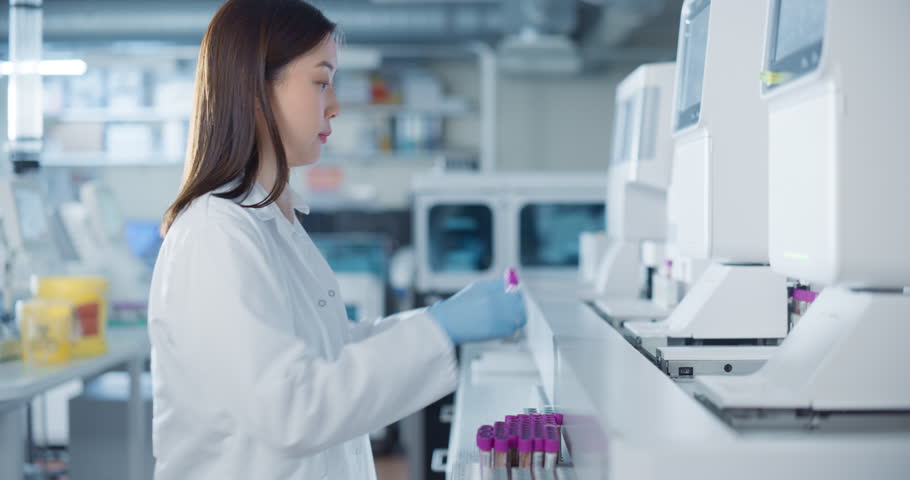 Portrait of an Asian Female Scientist in White Lab Coat Handling Multiple Test Tubes in a Modern Laboratory. Researcher Conducts Precise Experiments with the Help of Biomedical Research Techniques