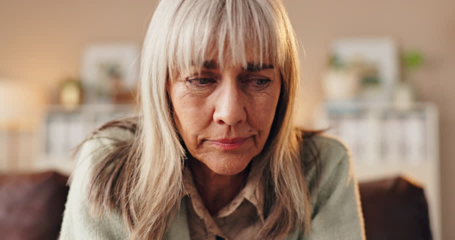 Senior, sad woman or depression with bad news, rejection or emotion on sofa at home. Elderly, female person or worry with concern or illness for cancer, diagnosis or life expectancy on couch at house