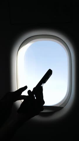Female Hands Typing on Mobile Phone in Airplane, Sunlight Shining Through Window, Peaceful In-Flight Moment During Aerial Travel Experience