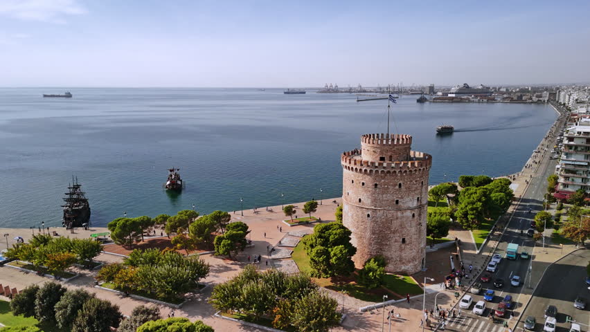 A breathtaking look at the White Tower surrounded by trees and blue waters, capturing the beauty of Thessaloniki