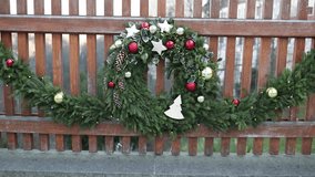 A beautifully decorated Christmas wreath with pine branches, red and gold ornaments, cones, and stars hanging on a wooden fence, creating a festive and cozy holiday atmosphere. - Powered by Shutterstock - Get 15% off with code: PIKWIZARD15