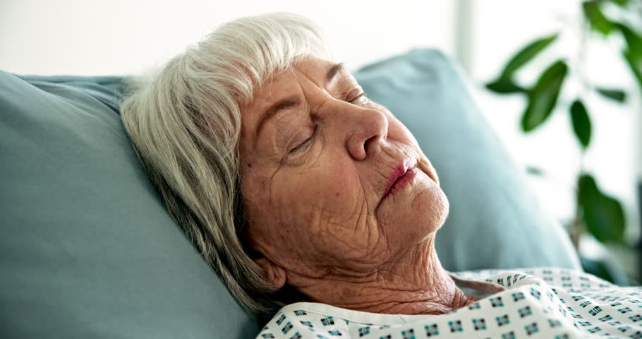 Sick, sleeping and senior woman in hospital bed for rehabilitation, tired or relax. Resting, disease and elderly patient in clinic for healthcare, fatigue or medical recovery after surgery treatment