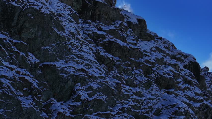 The Matterhorn famous mountain peak cliffside Riffelsee Lake Zermatt Swiss Alps aerial drone wind fog first fresh snow fall autumn winter blue skies morning Gornergrat railway Switzerland reveal