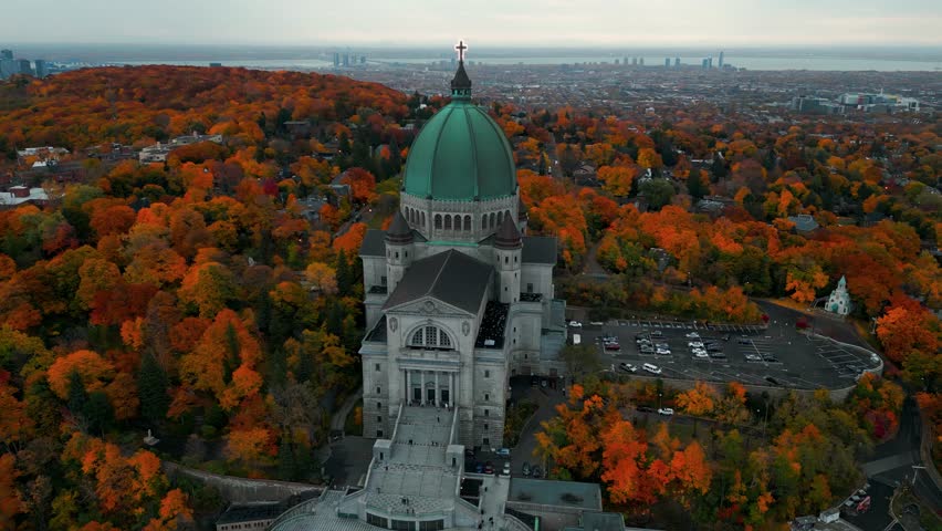 aerial shot around Saint Joseph Oratory in Montreal city revealing the city slyline in the backgound and the colorful landscape during fall season, Quebec Province, Canada