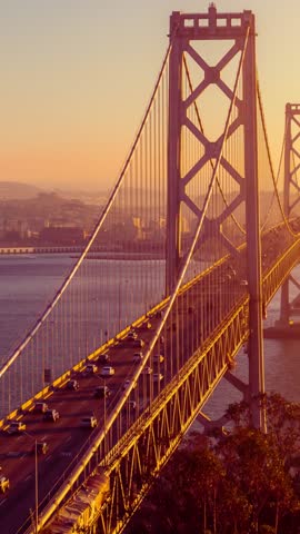 Traffic driving across the Bay Bridge towards downtown San Francisco at sunset. Vertical Video.