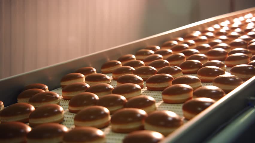 Hamburger buns on the baking line.Hot round delicious burger buns come out of the oven on the conveyor of the bakery or bakery production line