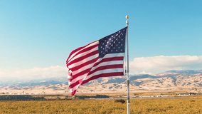 American Flag Waving in Wind, Patriotic Symbol Against Blue Sky and Mountains - Powered by Shutterstock - Get 15% off with code: PIKWIZARD15
