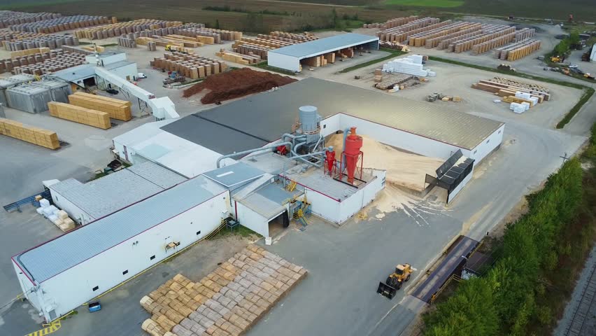 Aerial view of a sawmill equipped with a wood dryer, cyclones, a baghouse dust collector and a large wood storage yard. Quebec, Canada, 2024.