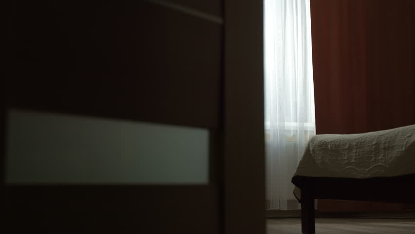 Sad and lonely woman standing at the window in the room. Concept of depression, problems and mental health. Female silhouette.