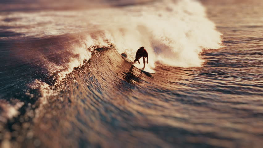 Surfer aerial. Surfer rides the wave in the Maldives. Aerial view of the rider on a wave during golden sunset
