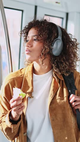 Young latin woman enjoying a green apple while commuting on public transportation during her daily routine. Young latin woman eating green apple on subway
