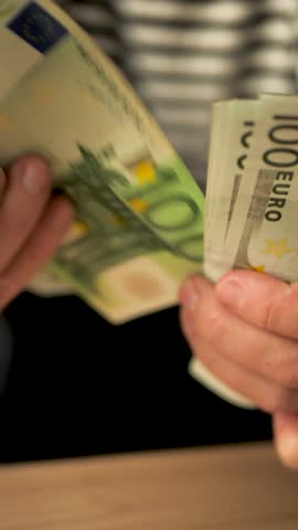 Vertical: White woman's hands holding euro banknotes counting the amount of money by hand. Woman counting euro cash after receiving unemployment benefit or salary