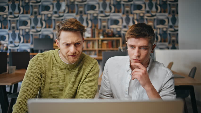 Focused designers looking computer at business place closeup. Creative serious coworkers staring monitor discussing at office. Team looking pc speaking together at modern agency. Occupation concept