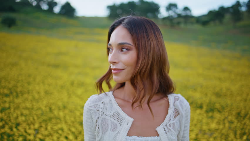 Portrait flowers girl posing in summer meadow. Gentle woman resting yellow field. Attractive romantic lady face looking camera at rural nature. Sensual model showing bloom kissing petals outdoors 