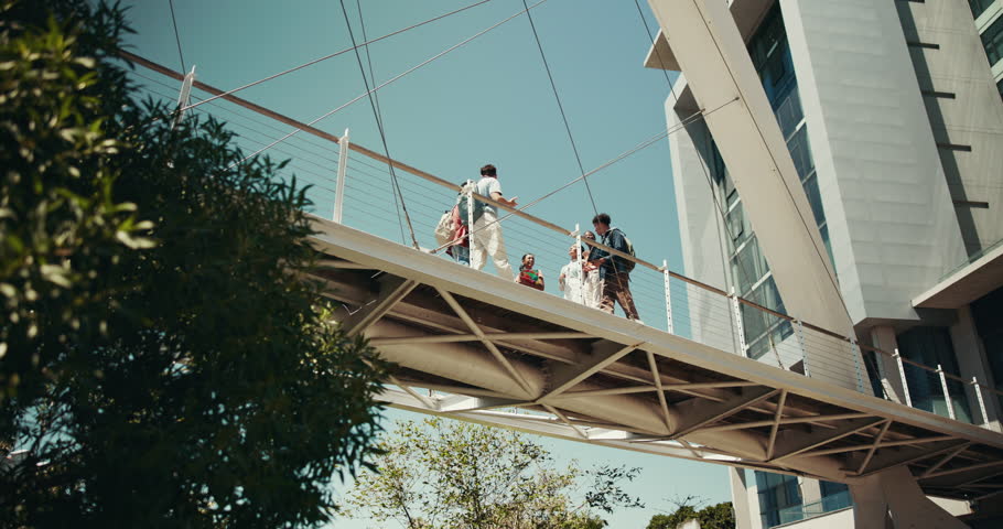Greeting, bridge and students with people from low angle in city for college campus, education and future. University, scholarship and community with friends in outdoor for youth and back to school