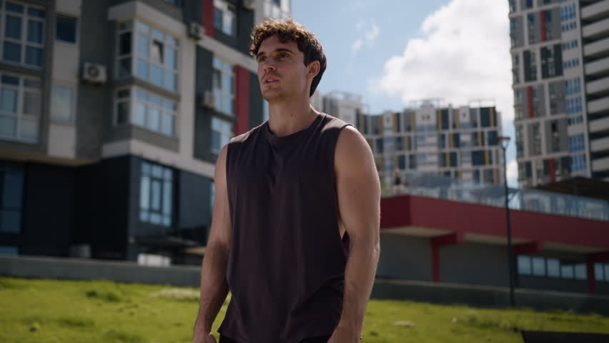 Confident Caucasian man hands on hips accomplishment achievement proud sportsman athlete male endurance strong motivation sport guy standing active training workout posing exercise urban city outdoor