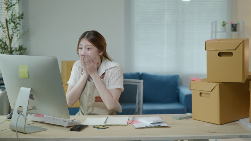 Female Owner SME Small and Medium Enterprises woman seller happy and excited for selling new products and receiving the orders from customer via smartphone and laptop on shopping online application.