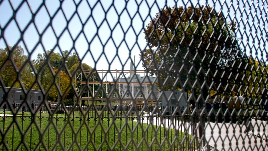 Static shot of the White House in the distance through a security fence